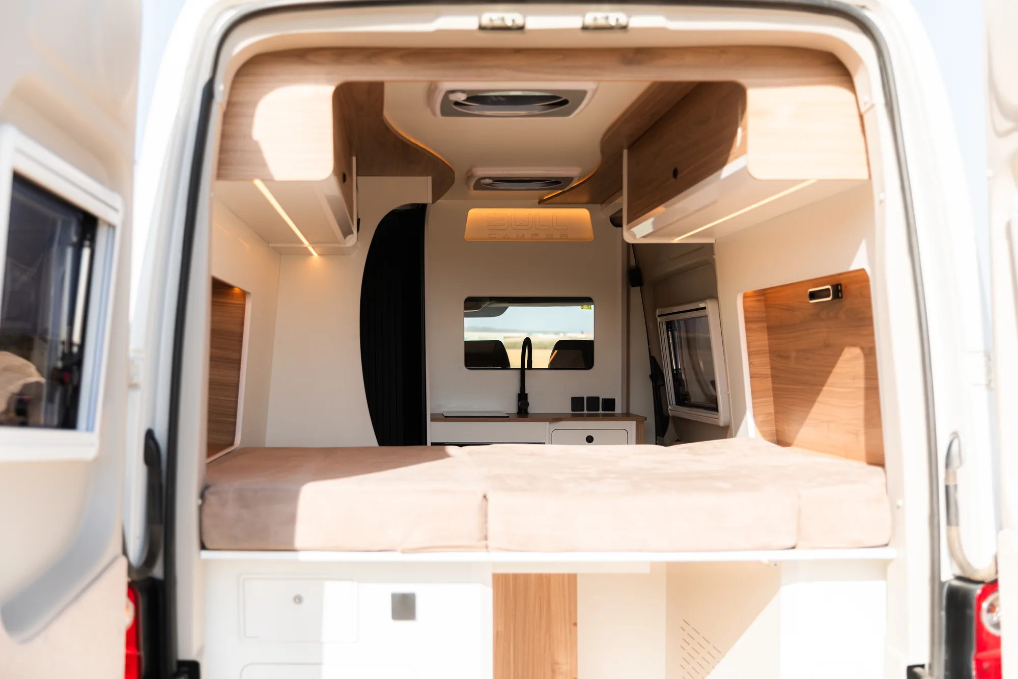 Puertas traseras abiertas de la Volkswagen Crafter con cama transversal y cocina al fondo